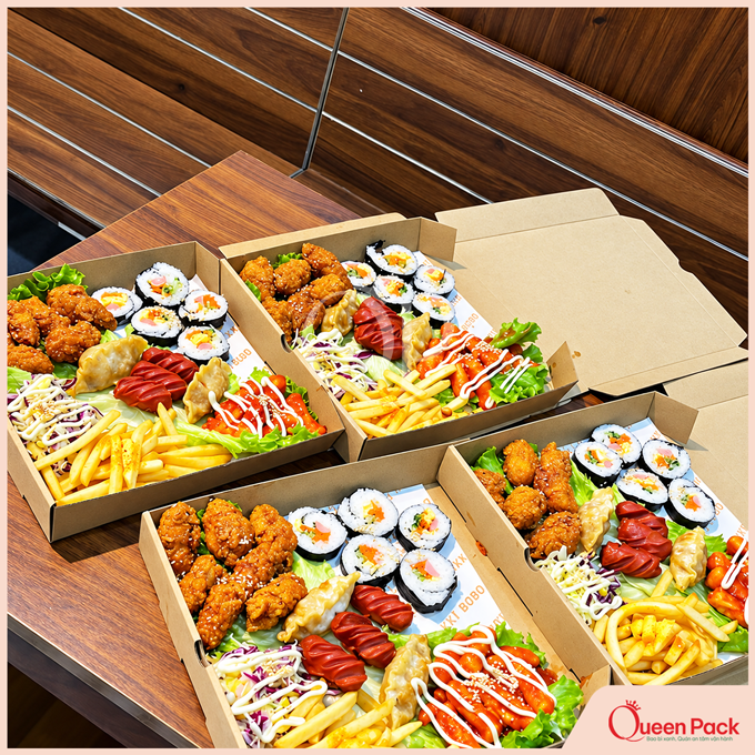 Hộp giấy đựng set đồ ăn vặt Hàn Quốc gồm gà rán, kimbap, xúc xích và khoai tây chiên.